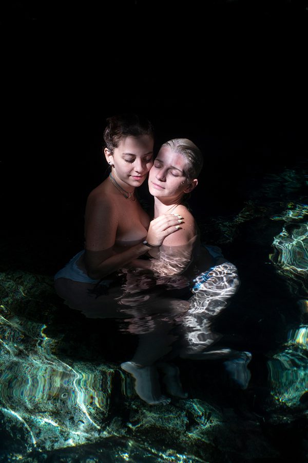 two girls in love and hugging in the water in a cenote in mexico