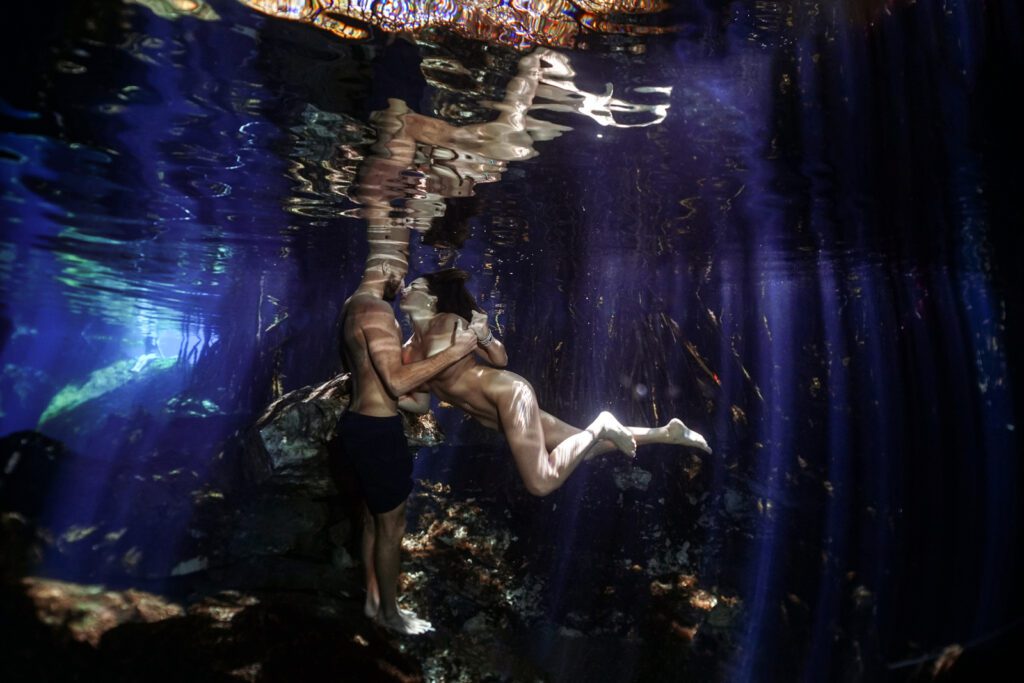an underwater couple in a magical setting like cenotes