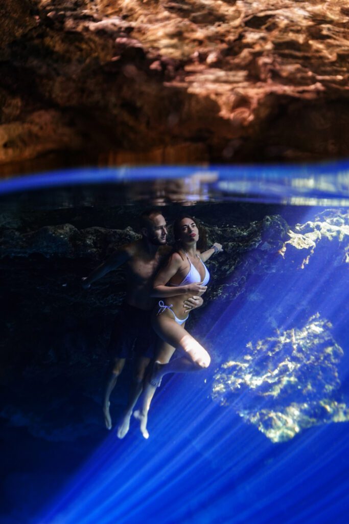 a couple posing underwater with a surreal blue light beam