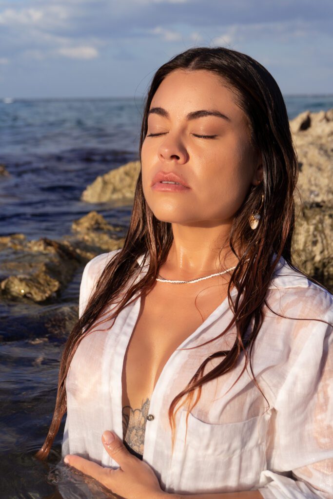 Relaxing beach moment with an individual resting on a rock, eyes closed. The photo focuses on the chest and head, capturing a tranquil scene by the sea