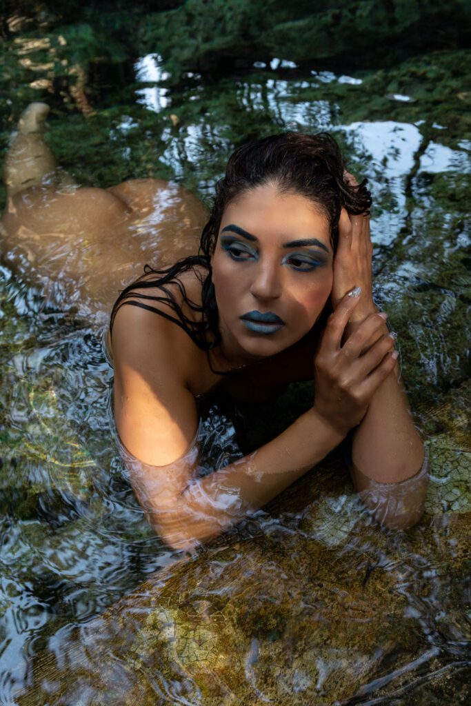 A beautiful girl lying naked in the water in a cenote, face down with her hand on her head, looks at left side.