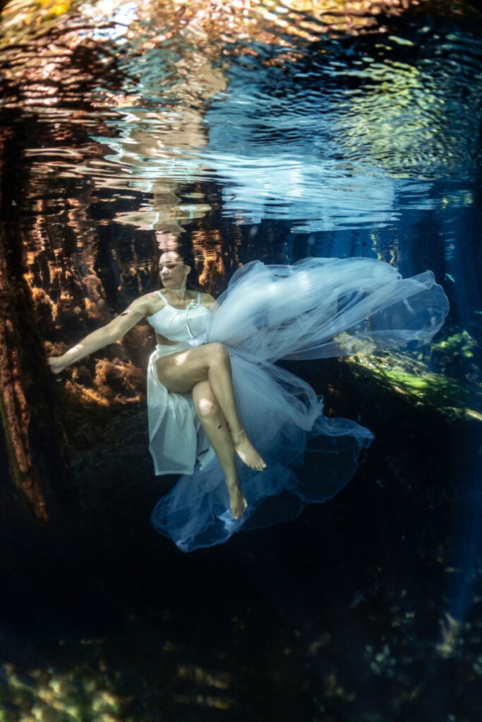 Portrait of woman underwater with natural light beam in Mexican cenote